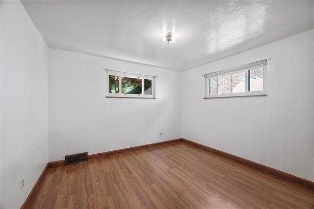 spare room with visible vents, baseboards, wood finished floors, and a wealth of natural light