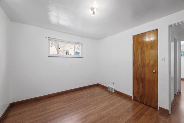 unfurnished bedroom featuring baseboards, wood finished floors, and visible vents