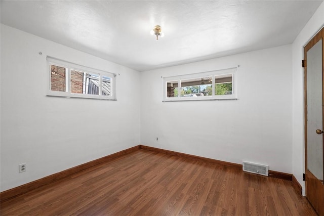 spare room featuring baseboards, wood finished floors, and visible vents