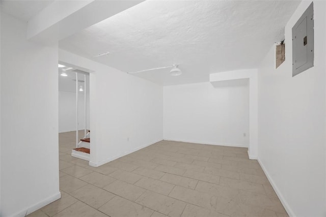 interior space featuring baseboards, electric panel, and a textured ceiling
