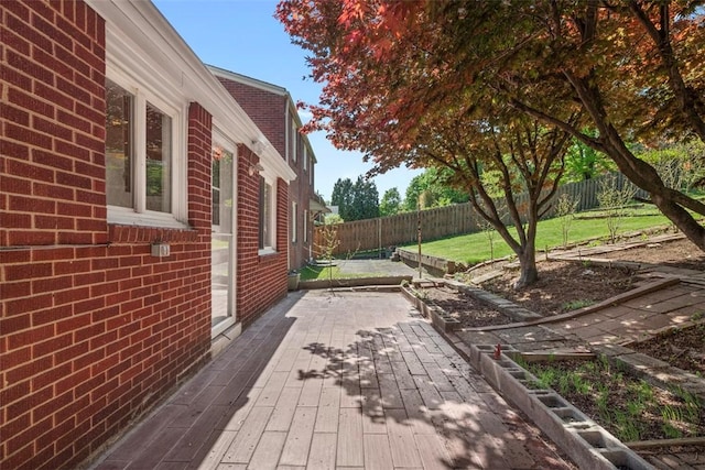 wooden terrace with a patio, a fenced backyard, and a lawn