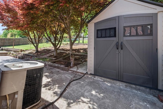 view of shed featuring fence and cooling unit