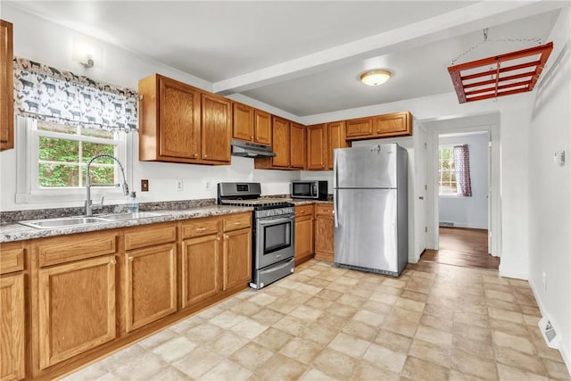 kitchen with under cabinet range hood, appliances with stainless steel finishes, plenty of natural light, and a sink