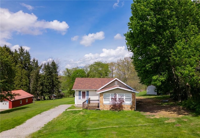 bungalow featuring driveway, an outbuilding, stone siding, and a front lawn