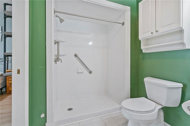 full bathroom featuring toilet, a shower stall, and tile patterned flooring