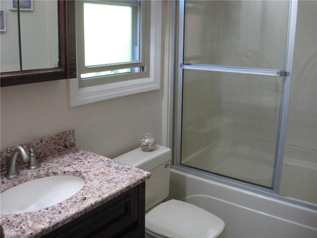 bathroom with vanity, enclosed tub / shower combo, and toilet