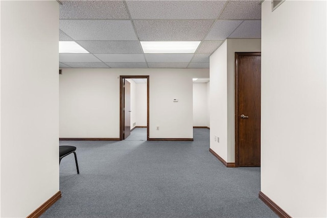 spare room with carpet floors, baseboards, and a drop ceiling