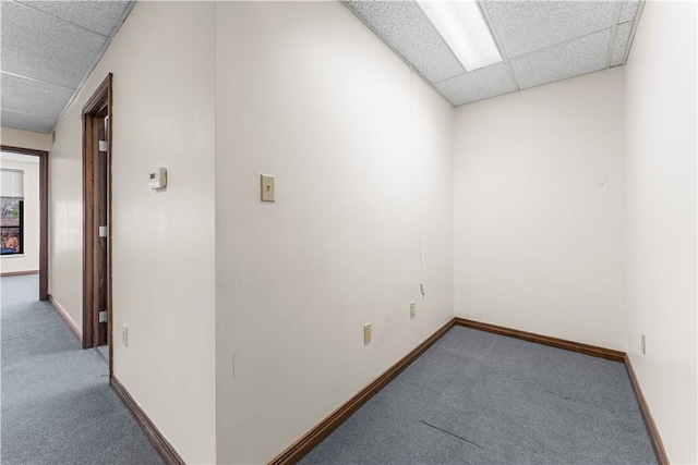 spare room featuring carpet floors, baseboards, and a paneled ceiling