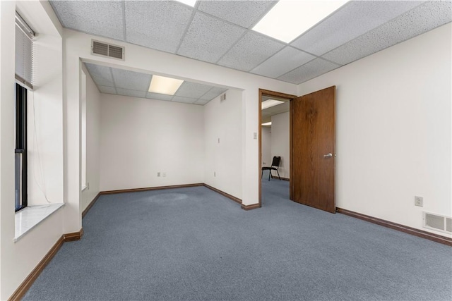 below grade area featuring baseboards, a drop ceiling, carpet flooring, and visible vents