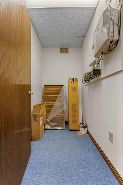 interior space featuring carpet flooring, visible vents, and a drop ceiling