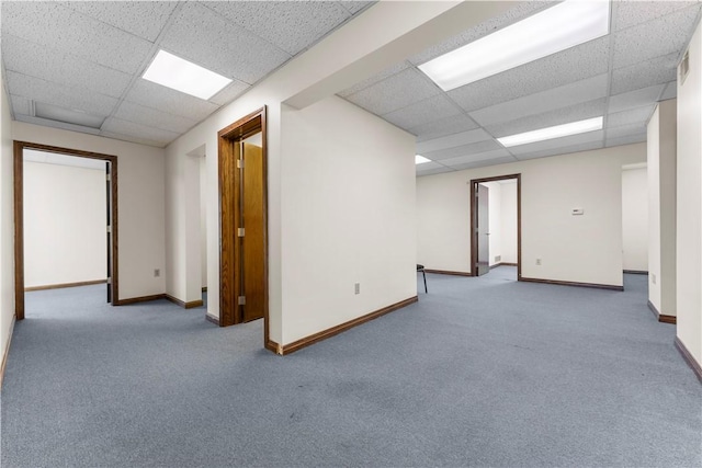 spare room featuring carpet floors, baseboards, and a paneled ceiling
