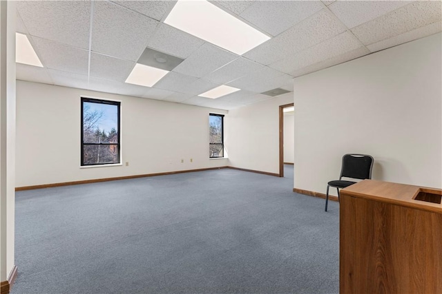 interior space featuring baseboards, a healthy amount of sunlight, and a paneled ceiling