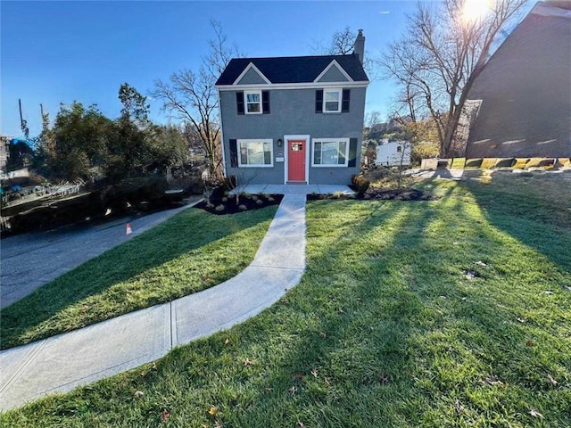 view of front of property featuring a chimney, stucco siding, and a front yard