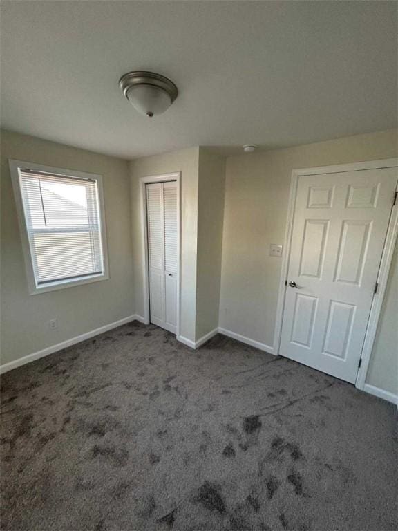 unfurnished bedroom featuring carpet floors, baseboards, and a closet