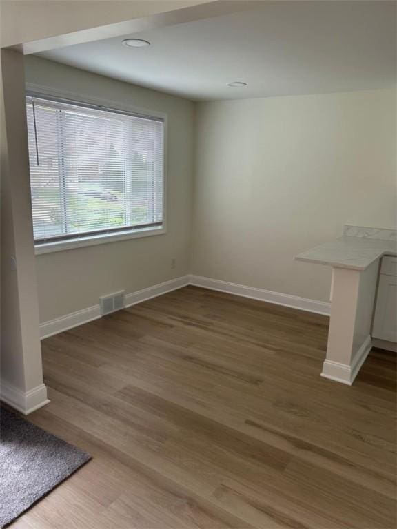 unfurnished dining area featuring baseboards, wood finished floors, and visible vents