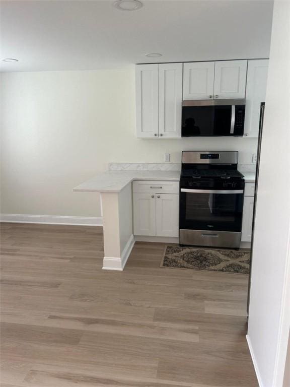 kitchen featuring baseboards, appliances with stainless steel finishes, and light wood-style flooring