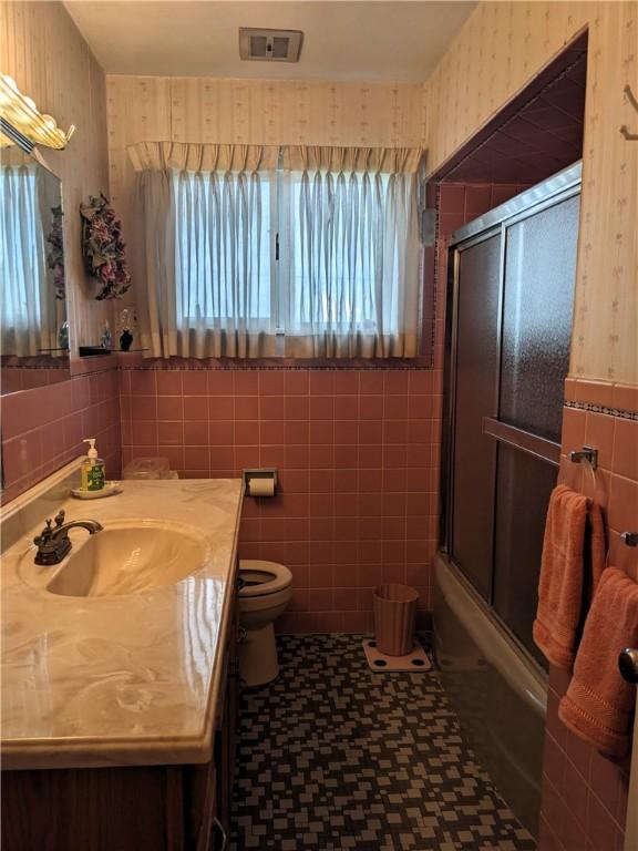 211 Wainwright Dr, Mckeesport, PA 15132 - full bathroom featuring tile walls, tile patterned floors, vanity, enclosed tub / shower combo, and wallpapered walls
