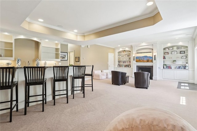 kitchen with crown molding, carpet floors, a kitchen bar, and built in shelves