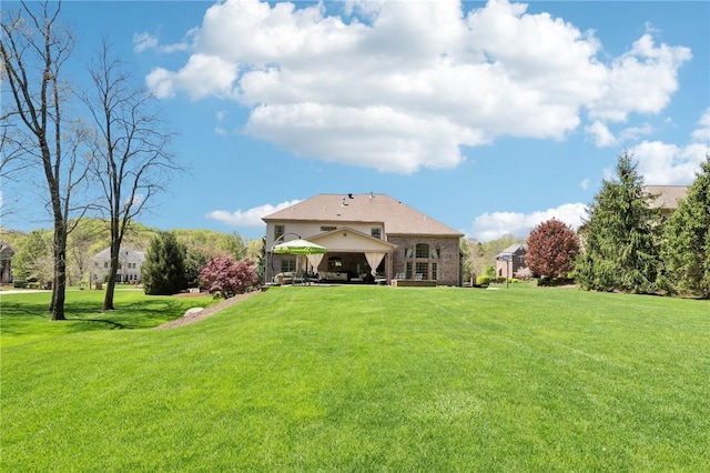 rear view of property featuring a gazebo and a yard