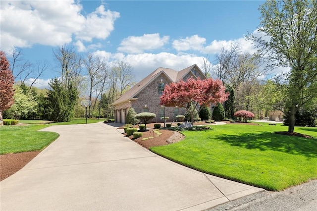 view of front of home with a garage, concrete driveway, a front lawn, and brick siding