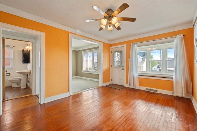 entryway with ceiling fan, visible vents, baseboards, ornamental molding, and hardwood / wood-style floors