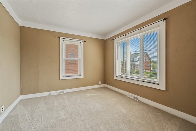 carpeted spare room featuring crown molding, baseboards, and visible vents