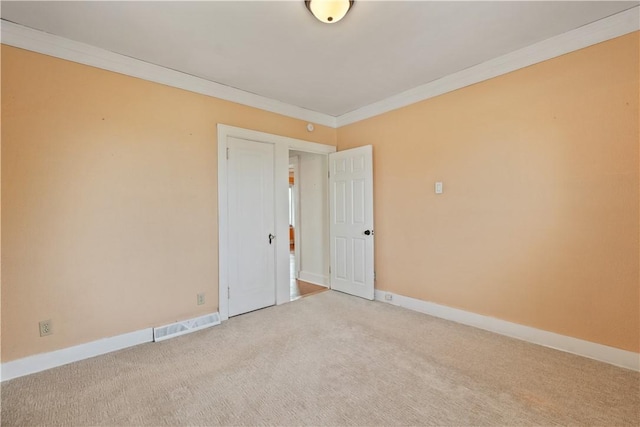 spare room with carpet floors, crown molding, visible vents, and baseboards