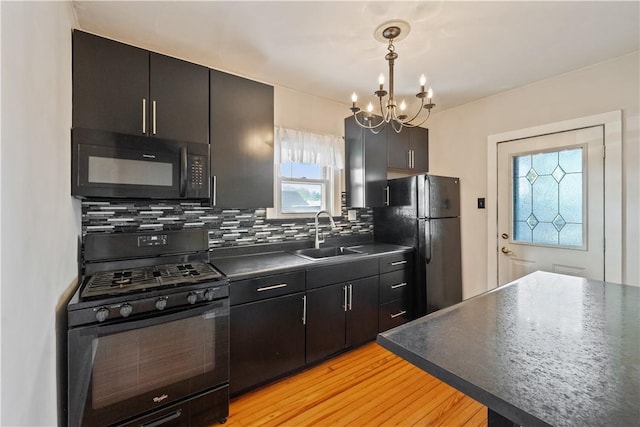kitchen with dark countertops, a chandelier, tasteful backsplash, a sink, and black appliances