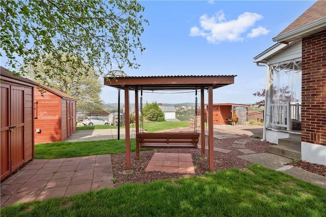 view of yard featuring a storage shed, fence, an outbuilding, and a patio area