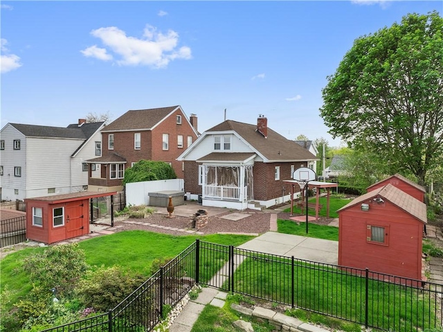 rear view of house with a fenced backyard, an outdoor structure, a yard, and a storage shed