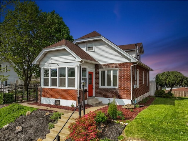 view of front of property with brick siding, a front yard, fence, and entry steps