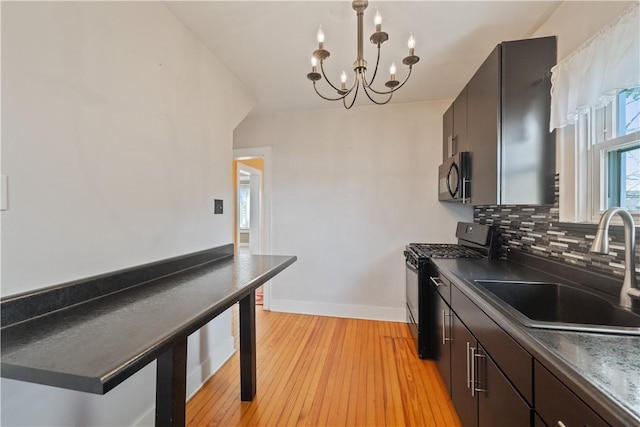 kitchen with an inviting chandelier, dark countertops, tasteful backsplash, a sink, and black appliances