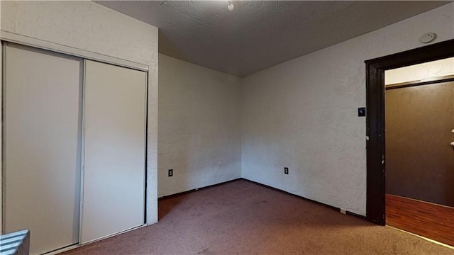 unfurnished bedroom featuring carpet floors, a textured wall, and a closet