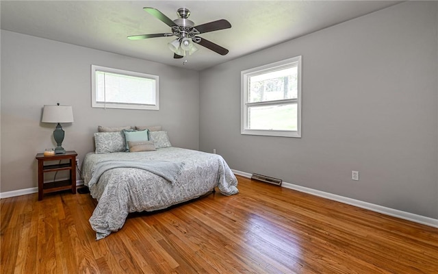bedroom with baseboards, multiple windows, and wood finished floors