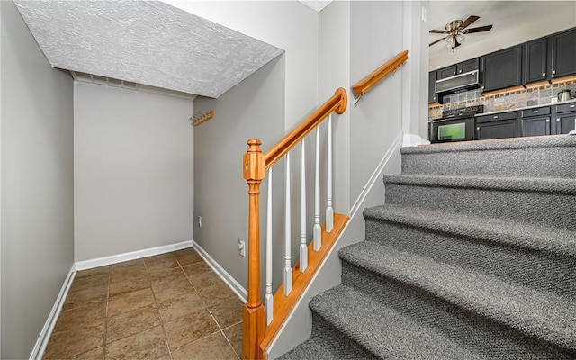 stairway featuring baseboards, a ceiling fan, and stone tile floors