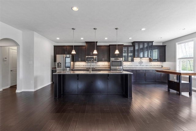 238 Gabriel Dr, Adams Twp, PA 16046 - kitchen featuring stainless steel appliances, arched walkways, a kitchen bar, decorative backsplash, and a kitchen island with sink