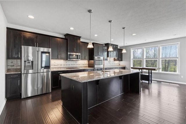 238 Gabriel Dr, Adams Twp, PA 16046 - kitchen featuring stainless steel appliances, a kitchen island with sink, backsplash, dark wood-style flooring, and light stone countertops