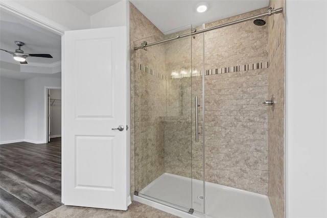 bathroom with baseboards, ceiling fan, a stall shower, and wood finished floors