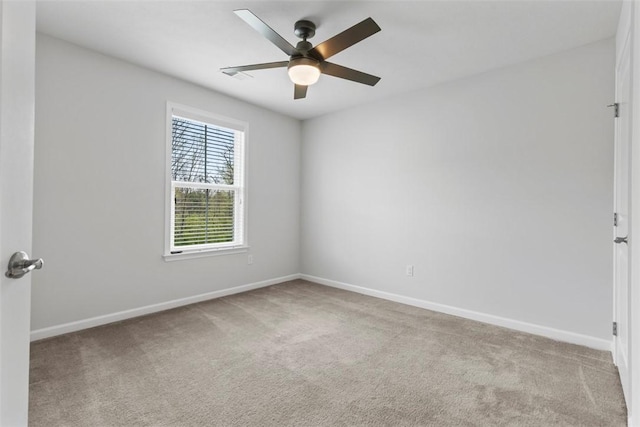 carpeted empty room featuring baseboards and a ceiling fan