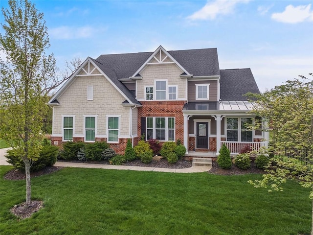 craftsman-style home with covered porch, a standing seam roof, brick siding, a front lawn, and a shingled roof