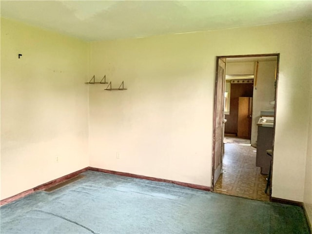 spare room featuring carpet floors and baseboards