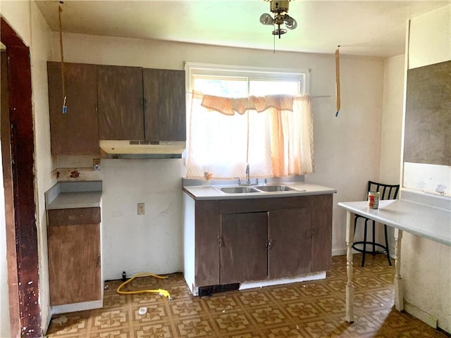 kitchen featuring under cabinet range hood, tile patterned floors, a sink, and light countertops