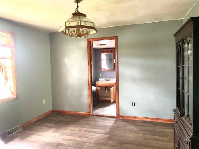 unfurnished dining area featuring visible vents, baseboards, wood finished floors, and a wealth of natural light