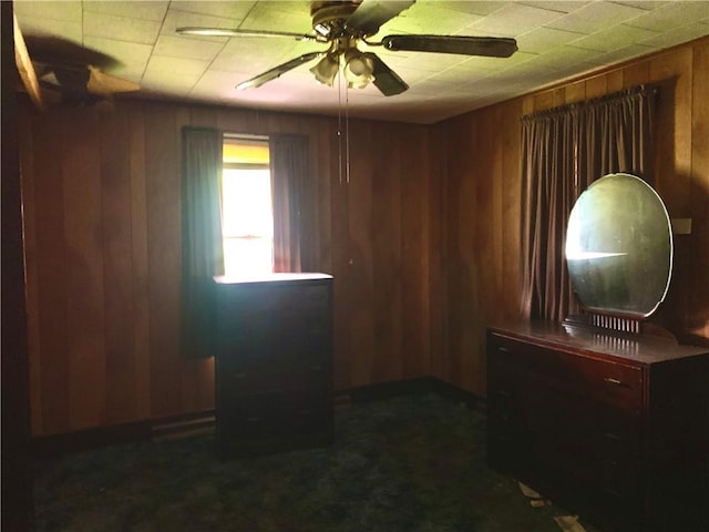 unfurnished room with a ceiling fan and wood walls