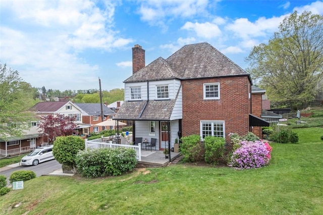 4044 Cloverlea St, Brentwood, PA 15227 - rear view of house with a porch, a high end roof, a chimney, brick siding, and a yard
