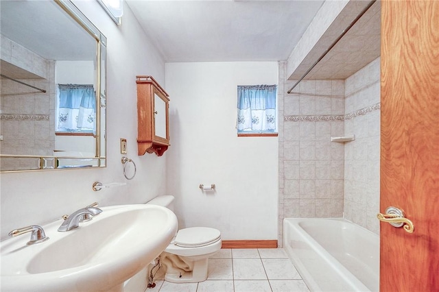 bathroom with a sink, toilet, tile patterned floors, baseboards, and  shower combination