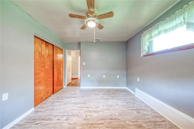 empty room featuring baseboards, light wood-style flooring, ceiling fan, and visible vents