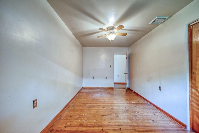 spare room with ceiling fan, visible vents, baseboards, and light wood-type flooring