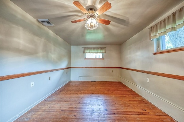 unfurnished room with baseboards, ceiling fan, hardwood / wood-style floors, and visible vents