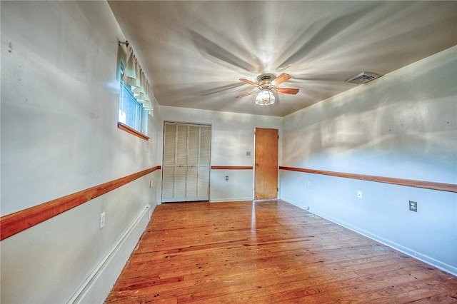 spare room with baseboards, a ceiling fan, wood finished floors, and visible vents
